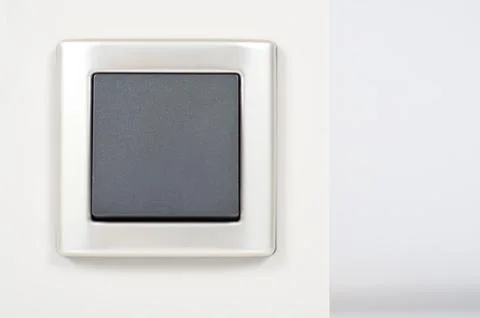 Light switch on the wall with grey button on silver frame Stock Photos
