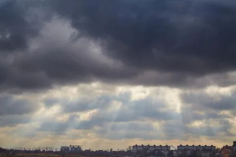 Light through dark clouds falls on the city, light breaks through the clouds  Stock Photos
