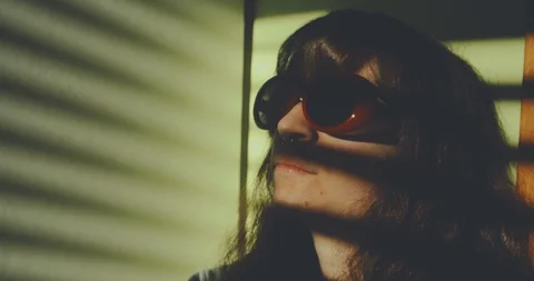 Light through window blinds frame a sad girl wearing red sunglasses. shot in slo Stock Footage 87466167