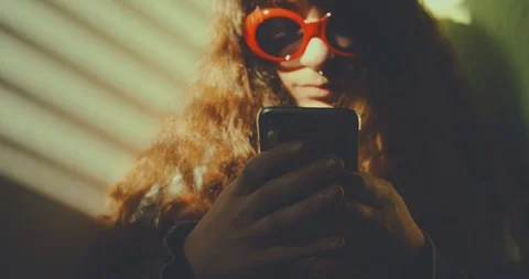 Light through window blinds frame a pierced girl wearing red sunglasses while su Stock Footage 87466792