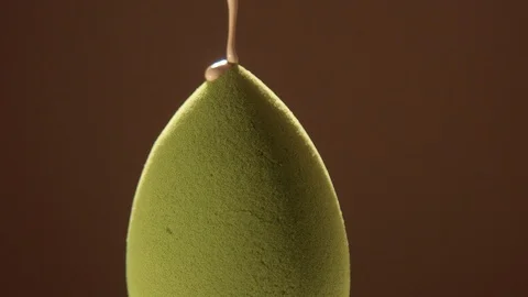 A light tone foundation pouring on green egg shaped blending sponge Stock Footage 128629997
