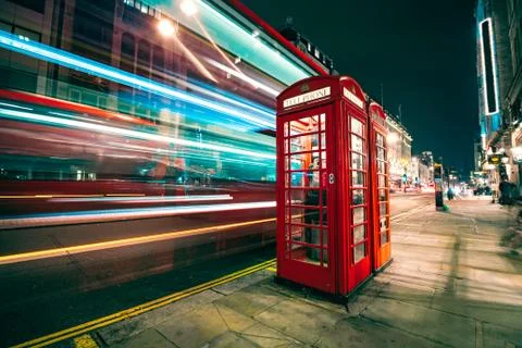 Light trails of a double decker bus next to the iconic telephone booth in London Stock Photos