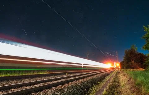 Light trails of a fast driving train at night with the stars of the milky way. Stock Photos