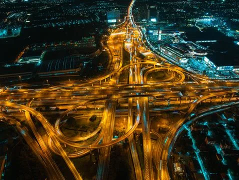 Light Trails Flow Through Complex Highway Interchange At Night High Angle Sho 库存照片