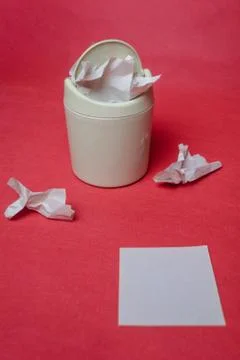 Light trash bin on a red background. Closeup of crumpled sheets of paper. Whi Stock Photos