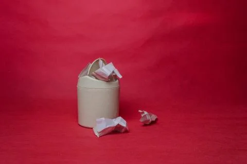 Light trash bin on red background. Closeup of crumpled sheets of paper. Conce Stock Photos