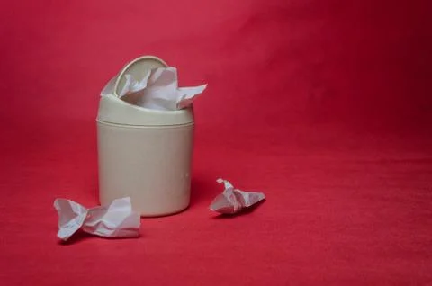 Light trash bin on red background. Closeup of crumpled sheets of paper. Conce Stock Photos