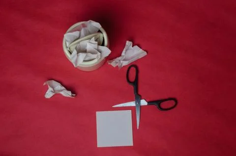 Light trash bin on red background. Closeup of crumpled sheets of paper and sc Stock Photos