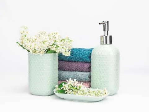 Light turquoise ceramic bathroom accessory set with multicolored soft towels Stock Photos