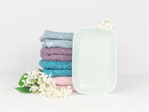 Light turquoise ceramic soap dish with multicolored soft towels and flowers Stock Photos