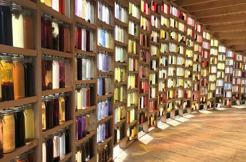 Light wall of colored bottles filled with organic material Stock Photos