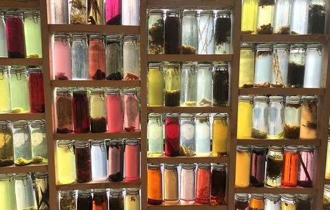 Light wall of colored bottles filled with organic material Stock Photos