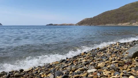 Light wave of surf on pebble shore. Splashes of sea foam create soothing noise. Stock Footage 309840867