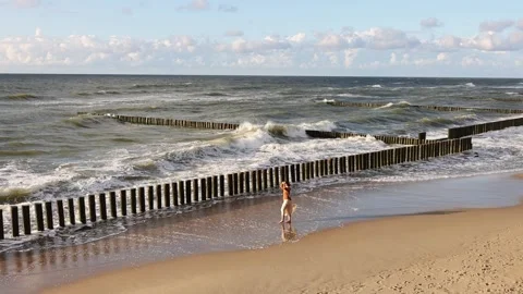 Light waves of the Baltic Sea caress the yellow sand of the coast against the Stock Footage 276683117