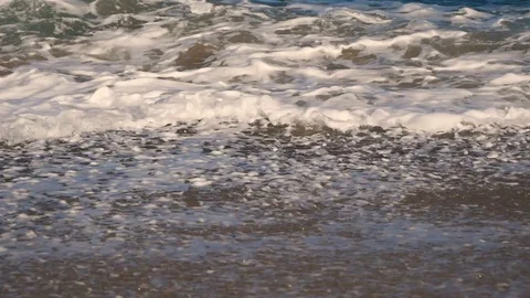 Light waves with foam on a sandy beach close-up 動画素材 127853241