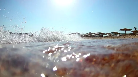 Light waves surf surf on the sandy beach with thatched beach umbrellas on a c Stock Footage 114801768