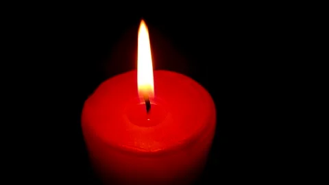 Light a wax candle with a lighter. A red candle burning in the dark. Stock Footage 317038748