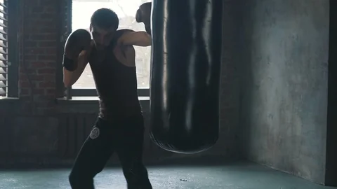 Light weight caucasian man hitting hard punching bag in slow motion Stock Footage 91587188