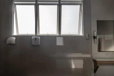 Light white bathroom interior with window and frameless mirror paired view an Stock Photos