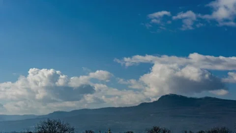 Light white clouds fly across a bright blue sky near small rocks. Timelapse Stock Footage 179360965