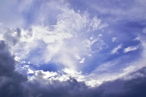 Light white clouds in the summer blue sky are illuminated by the bright sun b Stock Photos