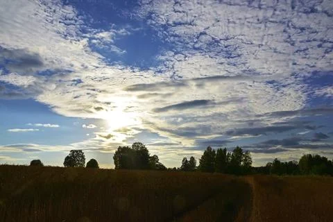 Light white clouds in the summer blue sky are illuminated by the bright sun b Stock Photos
