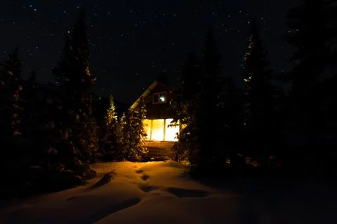 Light from the window of a forest hut under the night sky of the milky way in Stock Photos