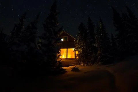 Light from the window of a forest hut under the night sky of the milky way in Stock Photos