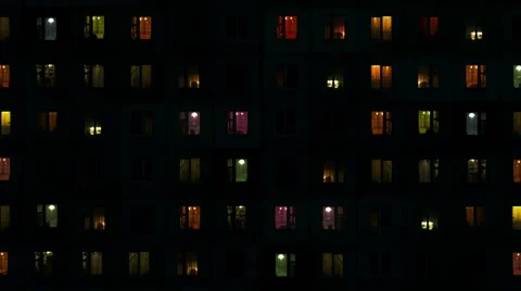 Light in the windows of high-density apartment block at night Stock Footage