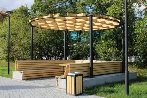 A light wooden gazebo with a bench, a table and an unusual hutch in a city pa Stock Photos