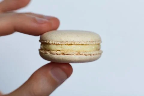 Light Yellow Macarons Between Two Fingers Stock Photos