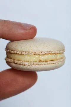 Light Yellow Macarons Between Two Fingers Stock Photos