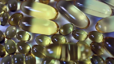 Light yellow oval capsules large and small rotate on a gray background. Real-tim Stock Footage 145107891