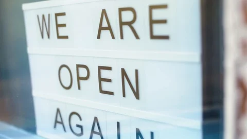 Lightbox with as sign we are open again behind a glass door of the cafe. We're Stock Footage 129576001