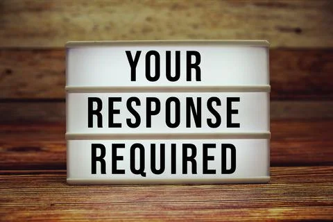 Lightbox with text "Your Response Required" on wooden background Stock Photos