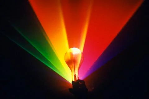 A lightbulb illuminated with an array of rainbow colors from a laser Fotos de archivo