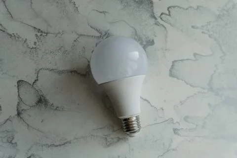 Lightbulb on a marble surface. Stock Photos
