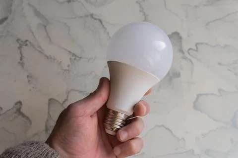 Lightbulb on a marble surface. Stock Photos