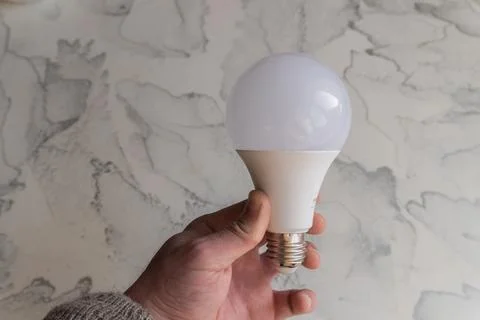 Lightbulb on a marble surface. Stock Photos
