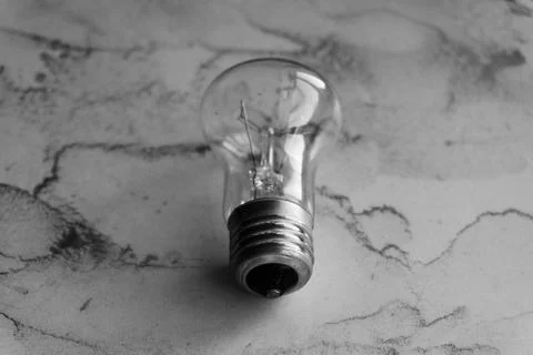 Lightbulb on a marble surface. Stock Photos