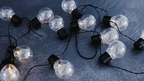 Lightbulb string lights shining on dark desk metaphor good ideas (horizontal  Stock Footage 116645976