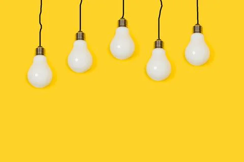 Lightbulbs hanging from black lines cable shape on a yellow background Stock Photos