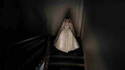 Lighted bride walks down dark stairs holding shining dress Stock Footage 126049718