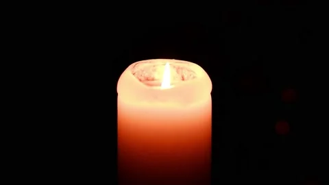 A lighted candle burns in complete darkness. Candle flame movement. Stock Footage 166696071