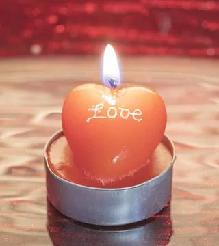 A lighted candle on a red background Stock Photos
