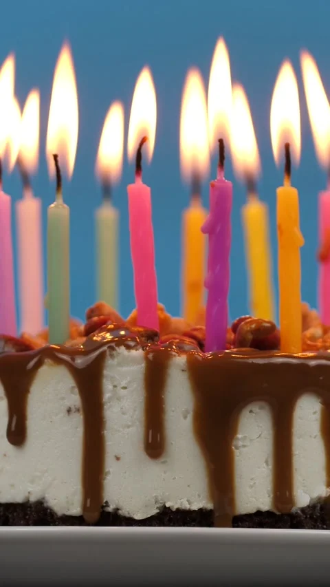 Lighted candles in a birthday cake rotation on a blue background. Candles in Stock Footage 277409679