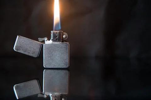 Lighted gasoline lighter with reflection on a dark background Stockfoto's