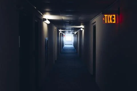 Lighted glowing red emergency exit signs in hallway with arrows pointing the way Stock Photos