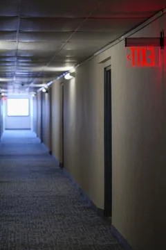 Lighted glowing red emergency exit signs in hallway with arrows pointing the way Stock Photos