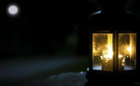 A lighted lantern against the background of the night sky with the moon. The Stock Photos